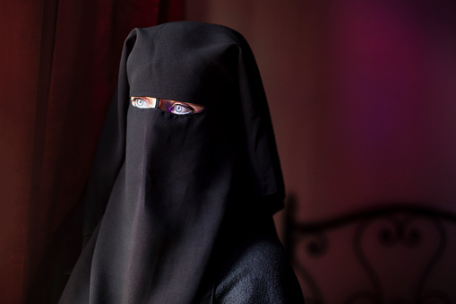 Arab woman in traditional clothing burqa at her home. Unrecognizable Middle Eastern female.