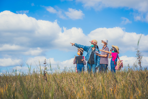 Children and mother learning and playing on grassland on blue sky background