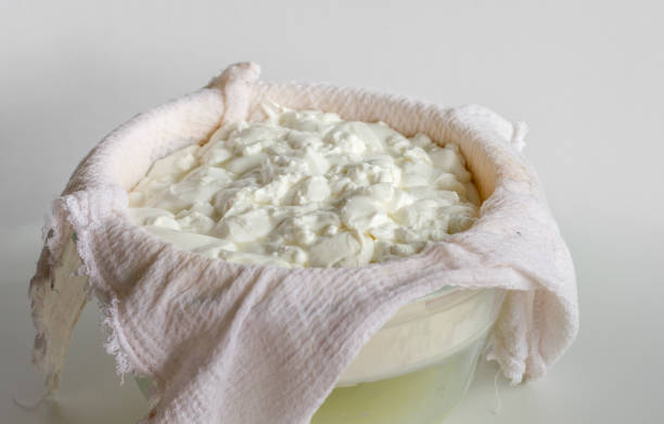 desorden de queso fermentado o requesón o yogur griego en una toalla de gofre para separarlo del suero de leche - cottage cheese fotografías e imágenes de stock