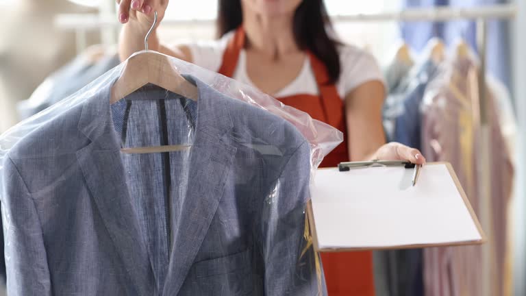 Dry cleaning administrator holds out suit with documents for signature