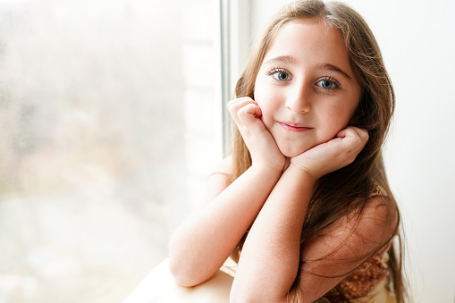 happy little girl a on white background sitting on the window sill