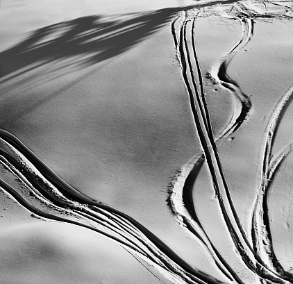 Black and white off-piste slope with track from ski and snowboard at night. View from above. High contrast.