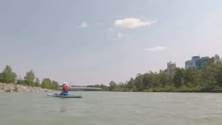 First person perspective from stand up paddleboard (SUP), floating on urban river