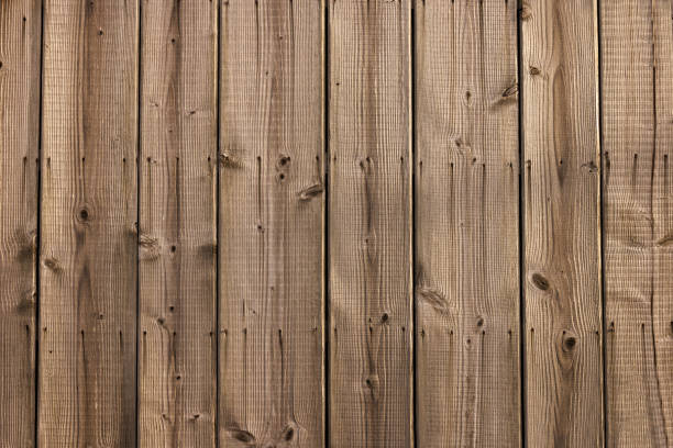 The rustic texture of a weathered timber fence, with prominent knots and visible grain patterns that have been accentuated by the aging process.