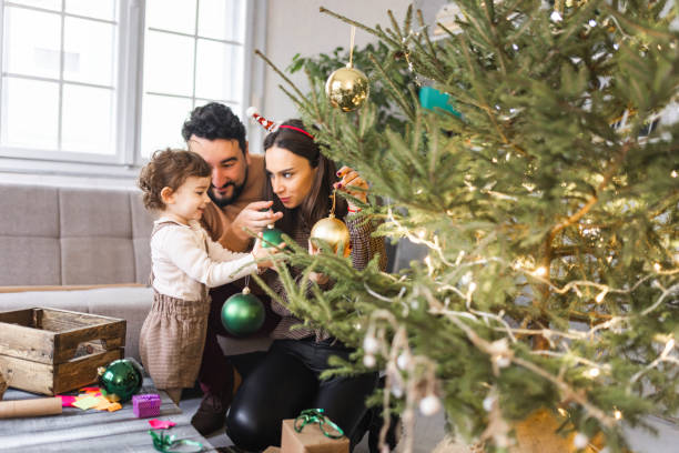 istock Young family decorating Christmas tree together 1359341343