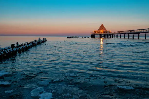 View over the water of the Baltic Sea to the illuminated famous pier of Heringsdorf / Germany in winter