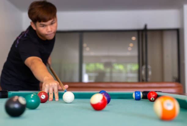istock A man in black shirt playing pool or billiard in a pool hall, focus on background, horizontal 1359344531