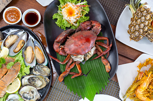 Fresh seafood with Thai style dipping sauce, grilled crab, deep-fried prawns or shrimps  and pineapple fried rice on wood table in restaurant, top view, horizontal