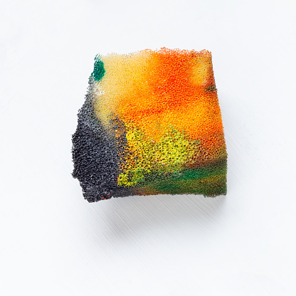 A piece of sponge in different bright paint colors. Abstract painting technique