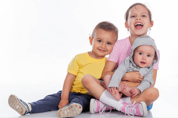Three little Latino cousins ​​all sitting on the floor looking at the camera while in a studio