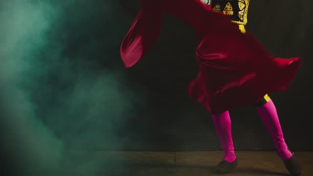 Male dancer or toreador imitating moves of matador bullfighter on black smoky background .  Man bullfighter dressed in bullfighting costume . Shot on ARRI Alexa cinema camera in Slow Motion