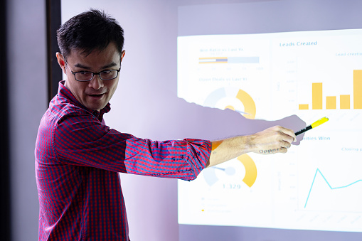 Chinese man giving a presentation with charts on projector screen