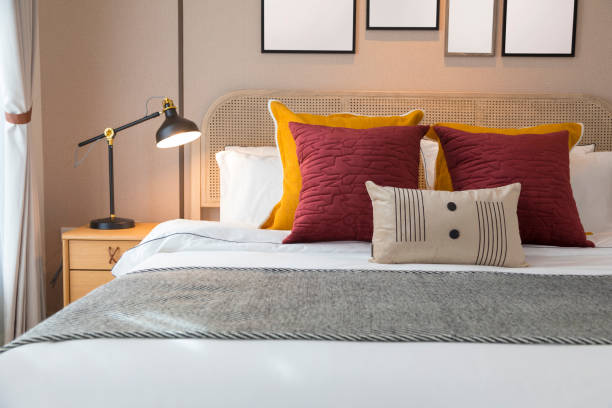istock Red and brown tone pillow bedding in modern bedroom interior with lamp on table. 1359350787