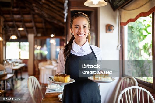 istock Smiling waitress serving dessert in restaurant 1359351220