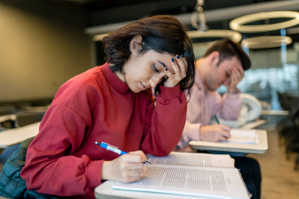 Young college girl taking exam and getting stressed stock photo