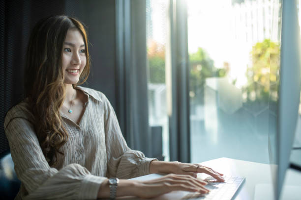 Chinese asian woman working on desktop computer in the morning stock photo