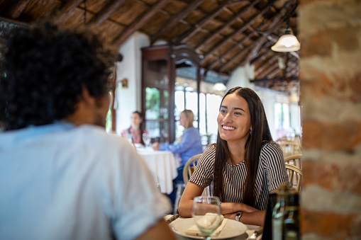 Young woman with boyfriend sitting at a restaurant table. Couple enjoying at a restaurant.