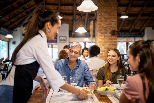 camarera que sirve comida a la familia en el restaurante - restaurant waiter table wait staff fotografías e imágenes de stock