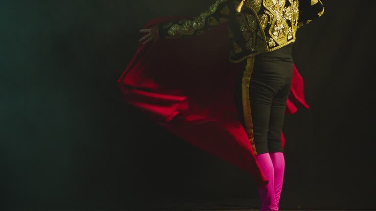 Male dancer or toreador imitating moves of matador bullfighter on black smoky background .  Man bullfighter dressed in bullfighting costume . Shot on ARRI Alexa cinema camera in Slow Motion