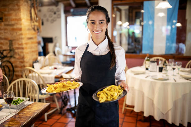 식당의 식탁에 음식을 가져가는 웨이트리스의 초상화 - women food smiling serving size 뉴스 사진 이미지