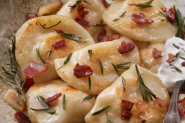 Roasted Garlic Cheddar Pierogi's Roasted Garlic Cheddar Pierogi's with Rosemary Butter, Bacon and Sour Cream Dumplings stock pictures, royalty-free photos & images