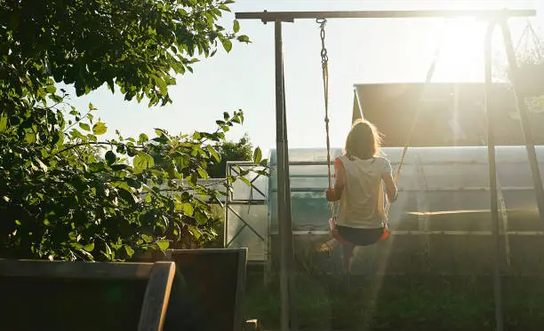 Childhood in the country. Girl is swinging on a swing.