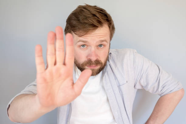 istock Calm, confident man makes a stop gesture, palm forward and looks seriously into the camera. 1359356361