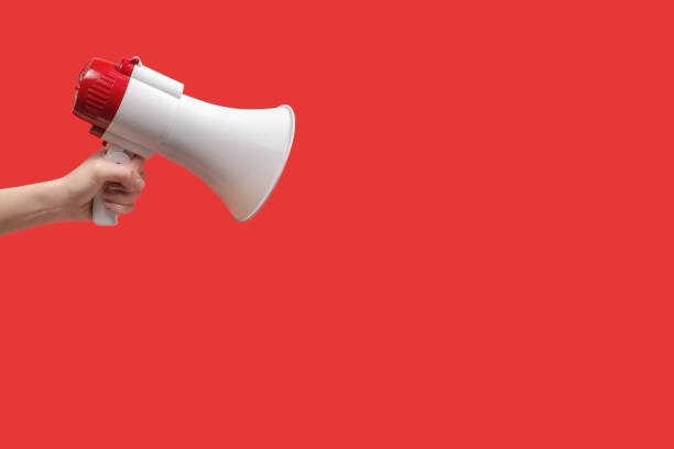 istock Megaphone in woman hands on a red background. 1359358045