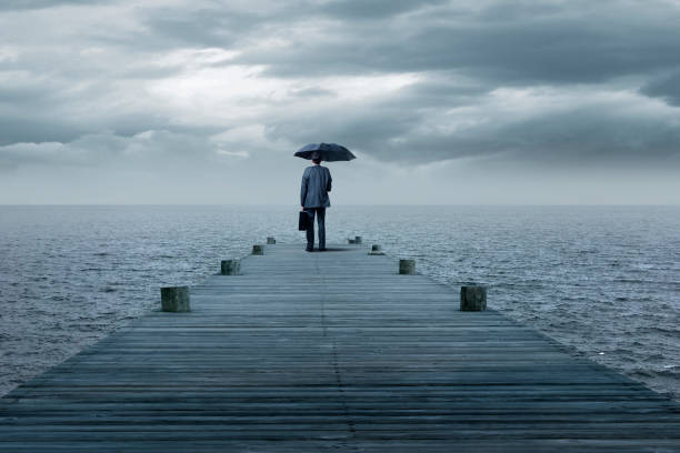 istock Man Standing With Umbrella At End Of Pier 1359358323