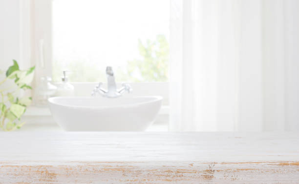 Wooden table top on blurred bathroom sink and curtained window stock photo