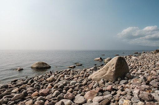 Magnificent landscape. Clean, calm sea and the rocky shore, skyline, with blue sky and white clouds in the summer sunny day.