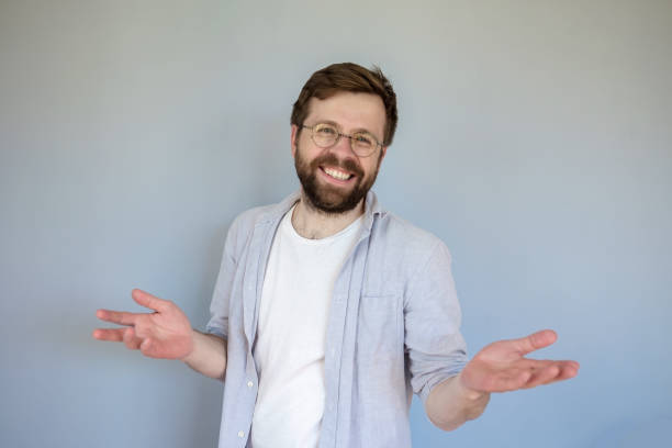 istock Friendly, charming man smiles cute and makes a gesture with hands. Gray background. 1359361586
