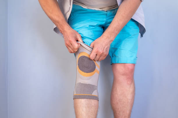 istock Man puts a special stabilizing brace on the injured knee joint. Studio, gray background. 1359365082