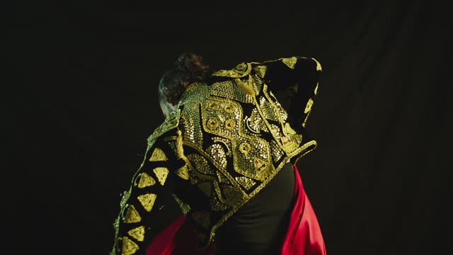 Male dancer or toreador imitating moves of matador bullfighter on black smoky background .  Man bullfighter dressed in bullfighting costume . Shot on ARRI Alexa cinema camera in Slow Motion