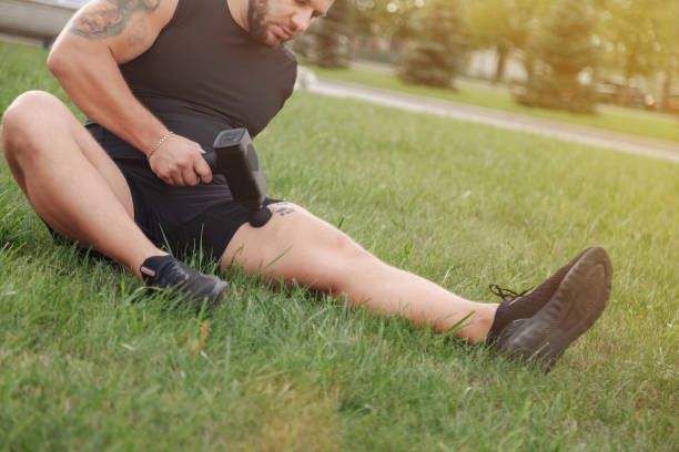 istock Man massages body with massage percussion gun device 1359366586