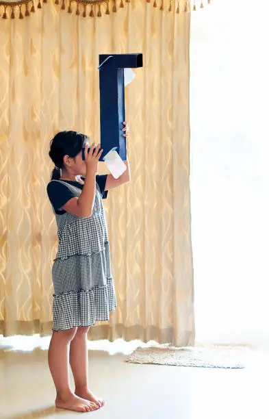 A girl looking through her DIY periscope in Khon Kaen, Khon Kaen, Thailand