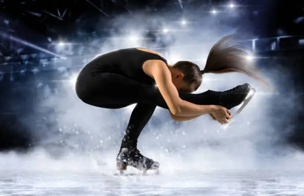 Sit spin. Woman figure skating in action on dark background. Sports banner. Horizontal copy space background