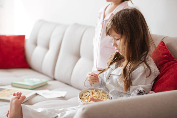 istock Cute girl eating popcorn at home 1359371715