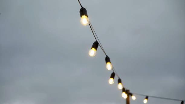 istock Garland of lamp bulbs outside. Decorative string light. Countryside, trees 1359372127