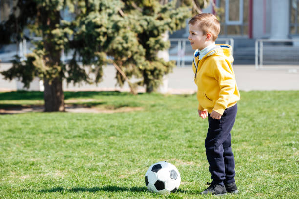 istock Cute boy playing football in park 1359372883