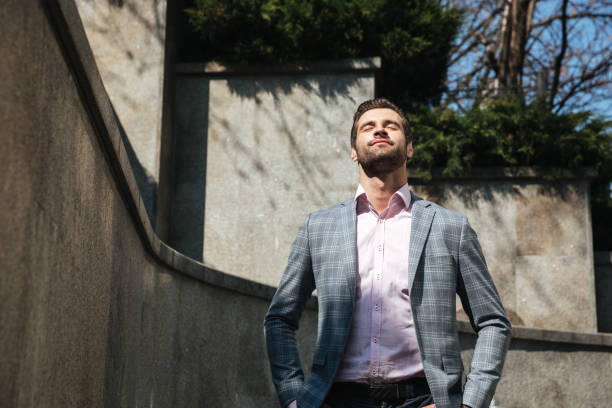 Image of handsome young businessman walking outdoors. Looking aside.