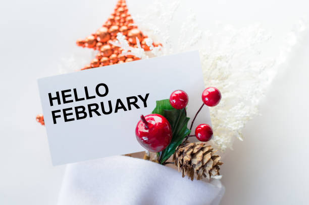 istock hello February text on a card next to Christmas decorations on a white background 1359374085