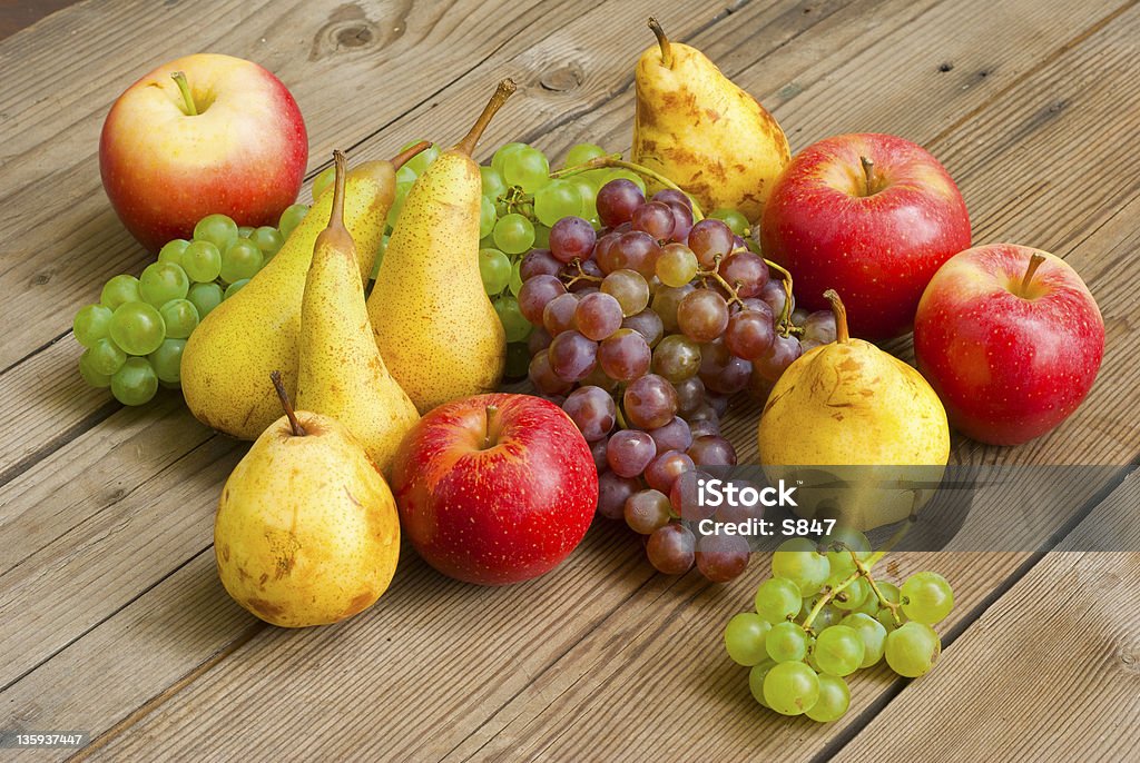 Manzanas uvas y peras en mesa de madera - Foto de stock de Alimento libre de derechos