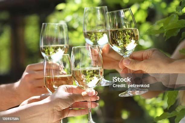 People Holding Glasses Of White Wine Making A Toast Stock Photo - Download Image Now