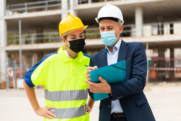 istock Man architect and a young woman engineer in masks discussing a construction project 1359376044