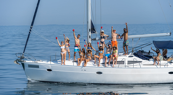 Large group of friends sailing and having fun on boat in summer. Youth and lifestyle concept.