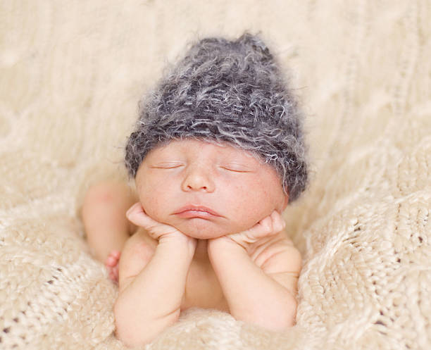 istock A newborn sleeping in a knit hat on a wool fabric 135937888