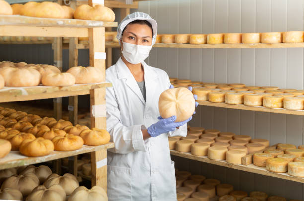 istock Woman cheesemaker in mask checking aging process of goat cheese 1359379995