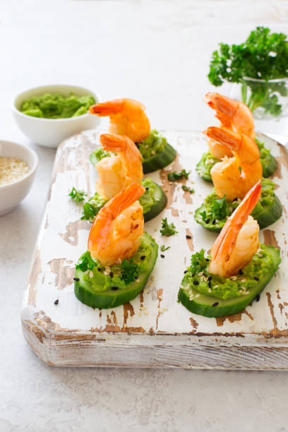 istock Cucumber avocado shrimp healthy appetizer on white cutting board close up 1359382626