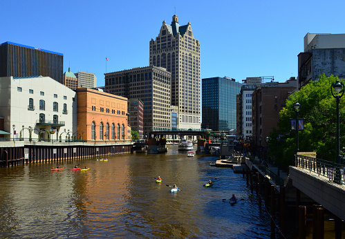 Milwaukee, Wisconsin, USA: kayaks and cruise boat near the Wells Street Lift Bridge on the Milwaukee River - buildings on the skyline include (left to right) BMO Harris Bank building, Wisconsin Bell building, 411 East Wisconsin Center, Milwaukee Repertory Theatre, 125 E Wells Street, Manufacturer's Home Building, First National bank Building, 100 East Wisconsin aka the Faison Building, Chase Tower, Rock Bottom Brewery and Empire Building - Milwaukee Riverwalk, Juneau Town neighborhood.